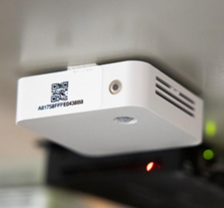 An indoor air quality monitoring device attached under a table.
